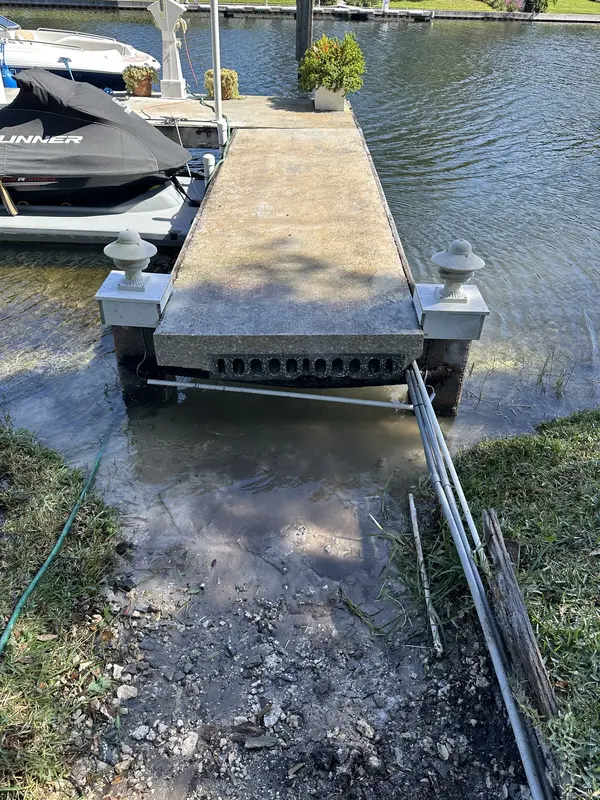 Concrete pier slab after demolition showing electrical conduits and corroded beam underneath