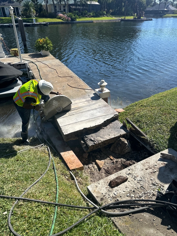 Valute Demolition crew performing precision concrete cutting on a waterfront pier slab to prevent stress on a corroded beam