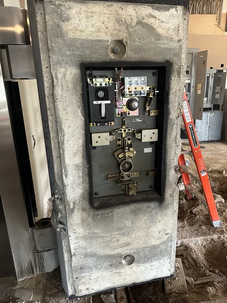 Commercial vault door removal in progress with exposed mechanical components inside concrete structure