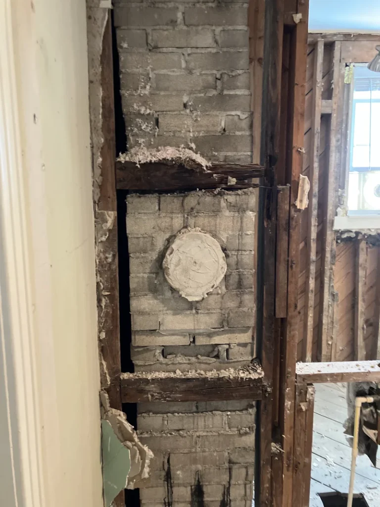 Interior view of masonry chimney structure inside a wall during demolition
