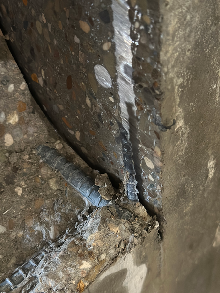 Close-up of reinforced concrete saw cut exposing aggregate and steel during vault demolition